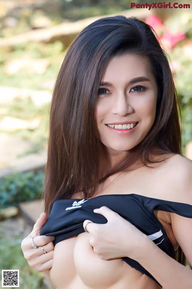 A woman in a black top is posing for the camera.