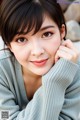 A woman in a gray sweater is posing for a picture.