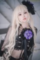 A woman with long blonde hair wearing a black dress and a purple flower.