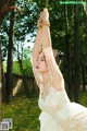 A woman in a wedding dress is tied up to a tree.