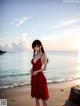 A woman in a red dress standing on a beach.