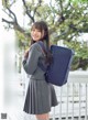 A woman in a school uniform holding a blue bag.