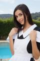 A woman in a black and white dress posing by a pool.