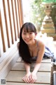 A young woman laying on a wooden bench.