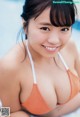 A woman in an orange bikini sitting by a pool.