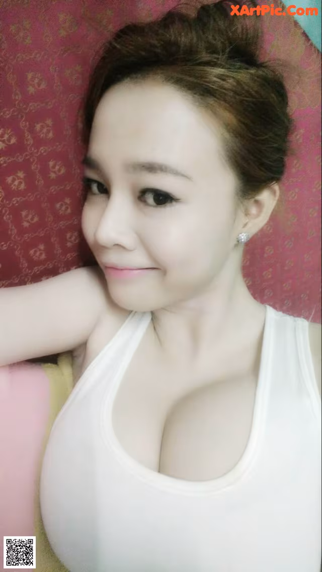 A woman in a white tank top posing for a picture.
