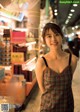 A woman in a plaid dress standing in front of a store.