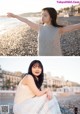 A woman sitting on a beach with her arms outstretched.