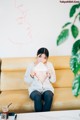 A woman sitting on a couch holding a piece of paper.