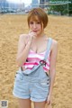 A woman in a pink and white striped tank top and denim overalls.