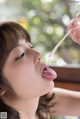 A woman is licking a stick with her tongue.