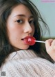 A woman holding a lollipop in her mouth.