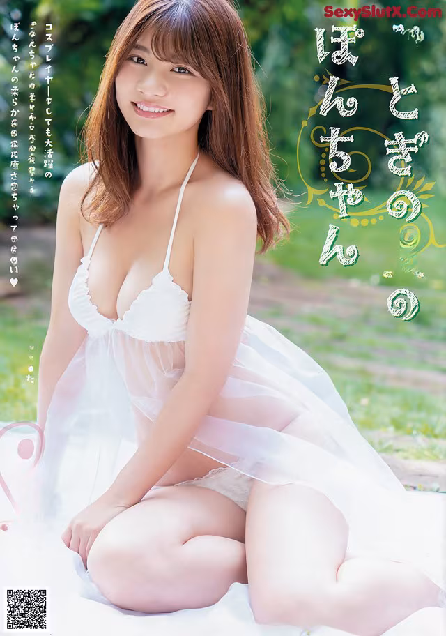 A woman in a white lingerie sitting on a blanket.