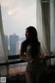 A woman in a white lingerie looking out a window.