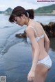 A woman in a blue and white bikini standing on a beach.