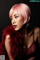 A woman with pink hair wearing a red fur stole.