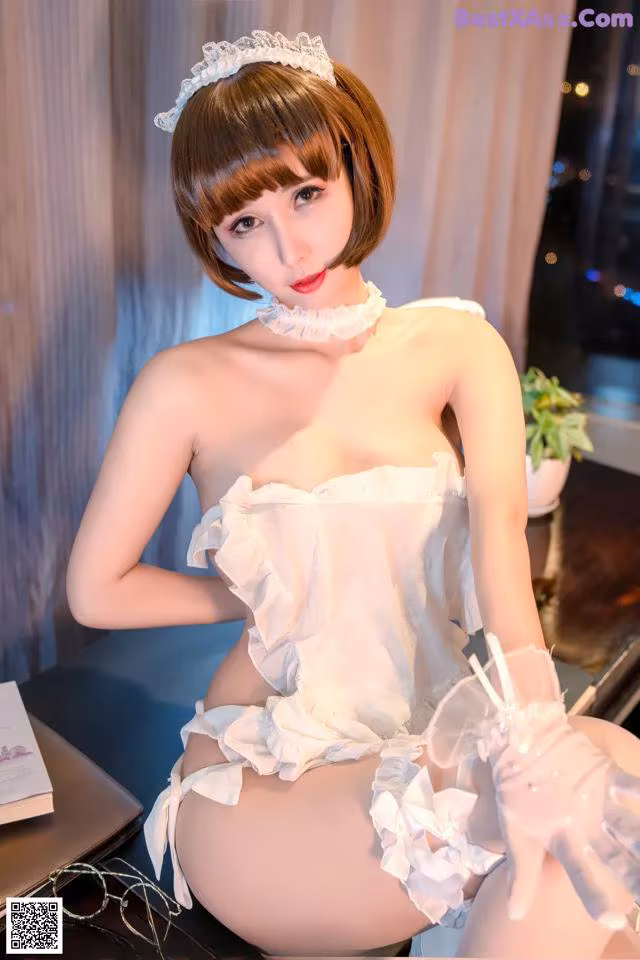 A woman in a white dress sitting on a table.