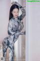 A woman in a long dress leaning against a wall.